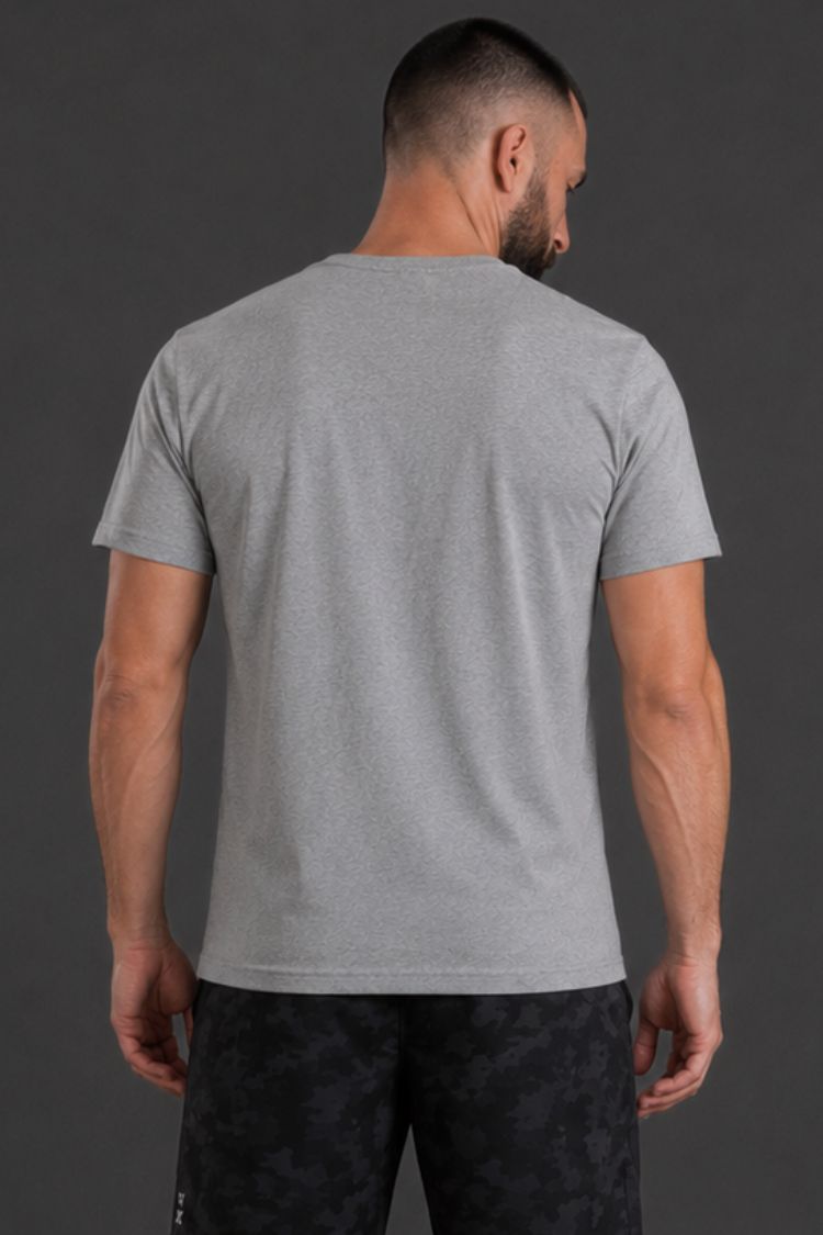 Man wearing a gray t-shirt and black pants against a dark background