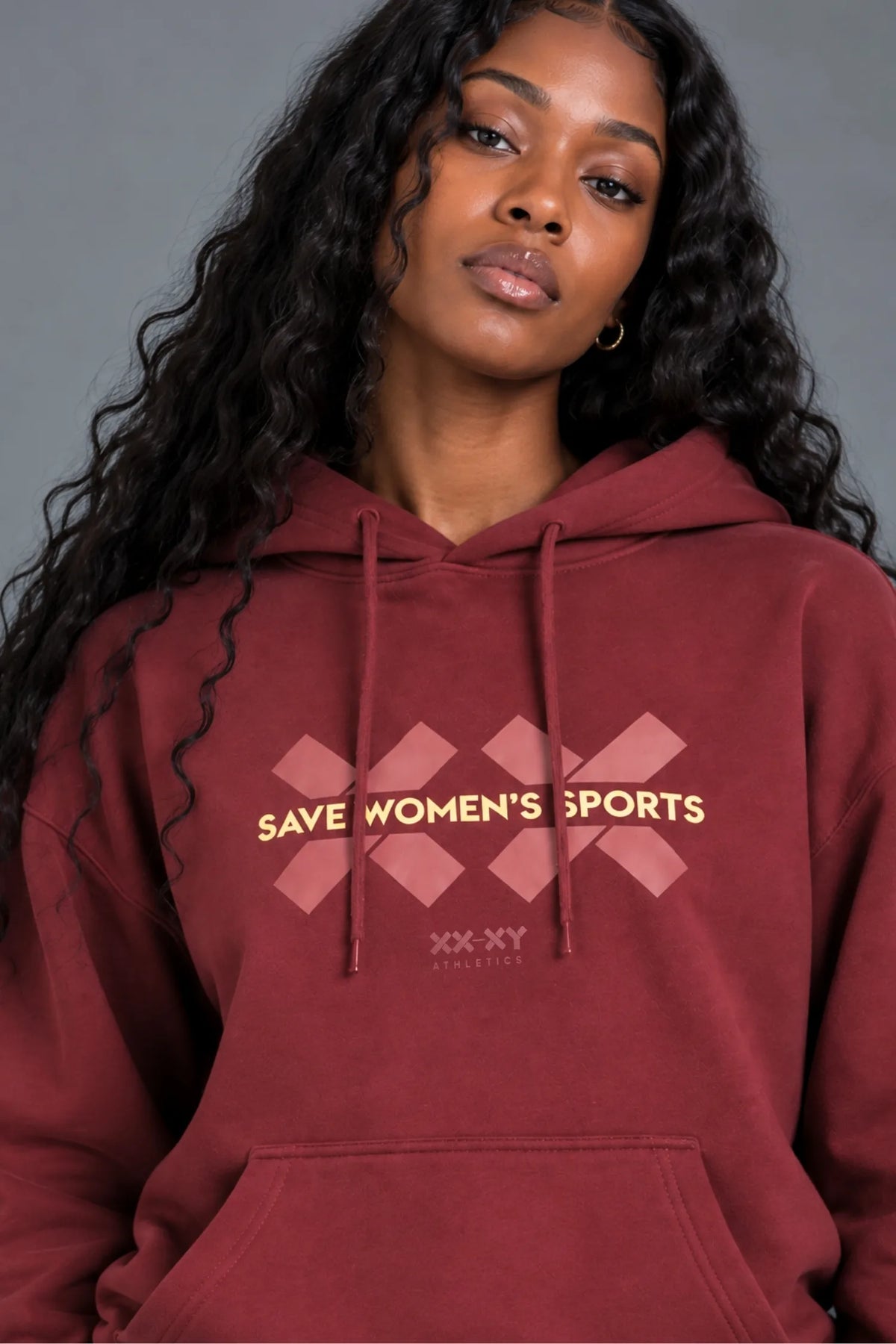 Black woman wearing a burgundy Save Women’s Sports graphic hoodie and matching sweatpants. || Red Wine