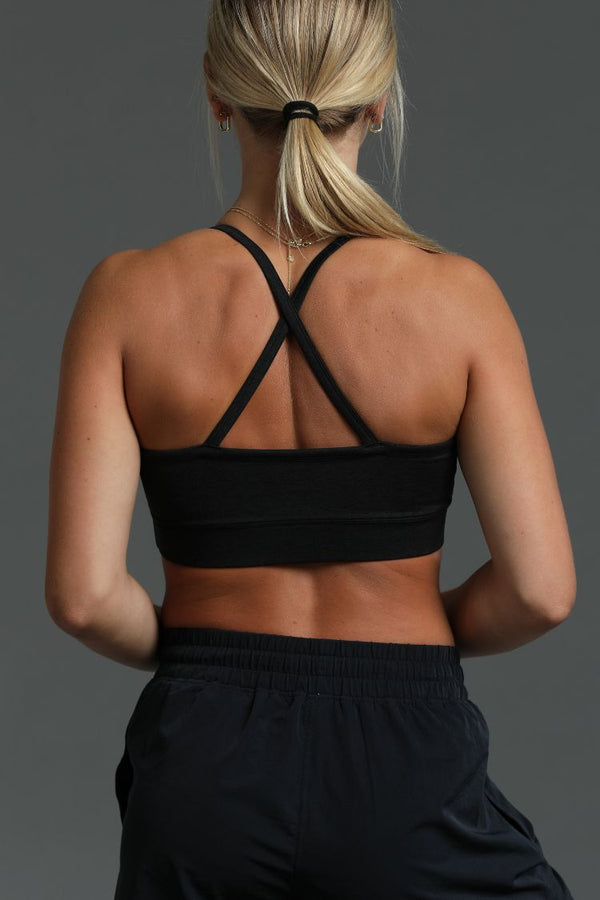 Person wearing a black sports bra and black shorts on a gray background || Black Heather