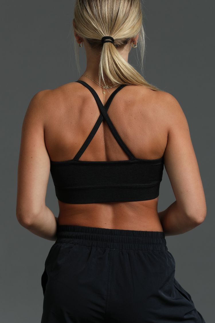Person wearing a black sports bra and black shorts on a gray background || Black Heather
