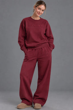 Woman wearing burgundy XX-XY Athletics wide-leg fleece sweatpants with tonal embroidered logo. || Red Wine