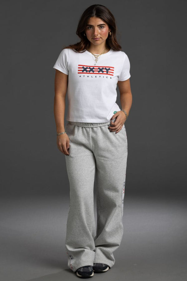 Woman wearing a white t-shirt with an American flag design and gray sweatpants || White