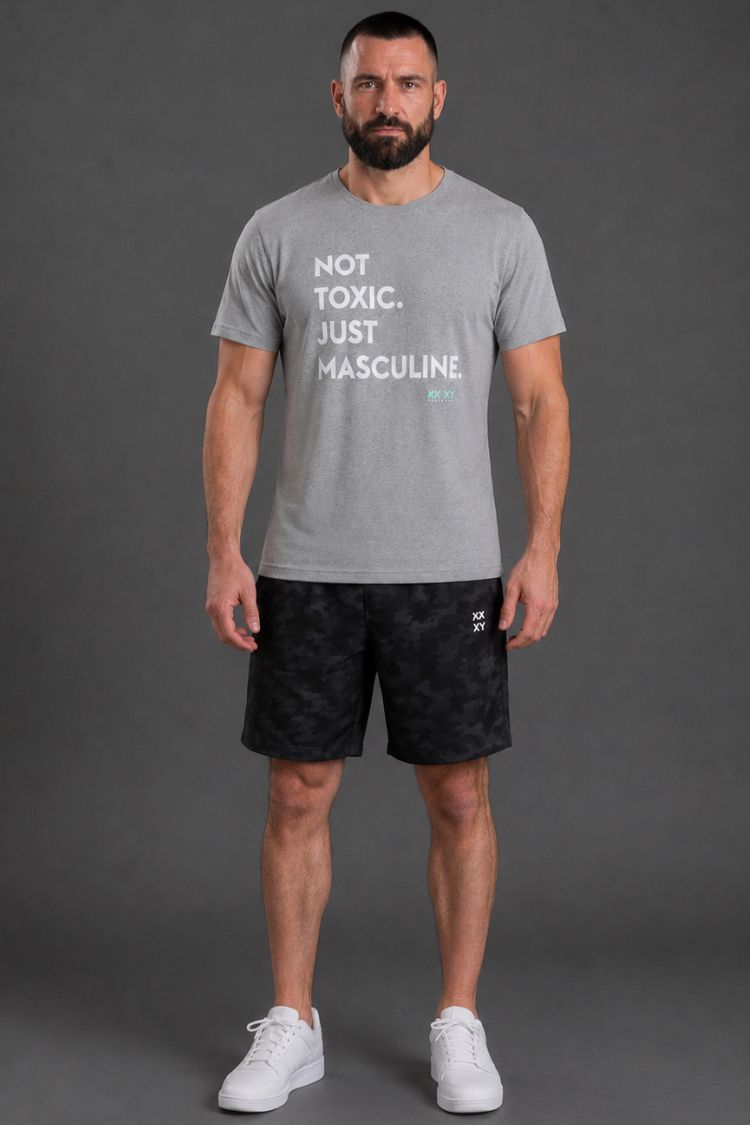 Man wearing a gray t-shirt with text and black shorts on a gray background