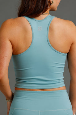 Person wearing a light blue athletic top and shorts on a gray background || Underseas