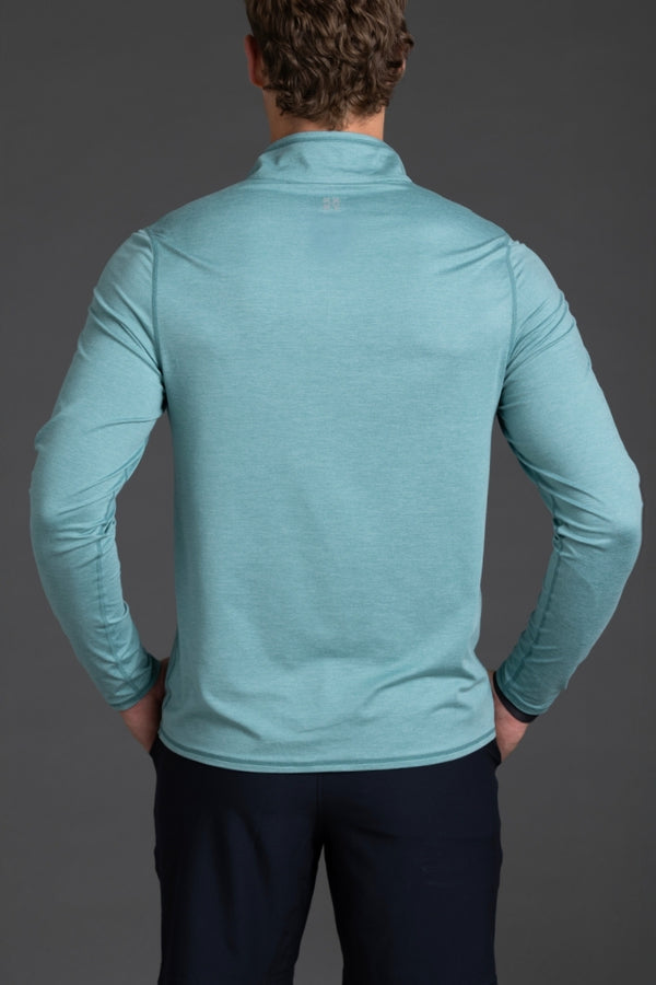 Person wearing a teal long-sleeve shirt against a gray background || Underseas