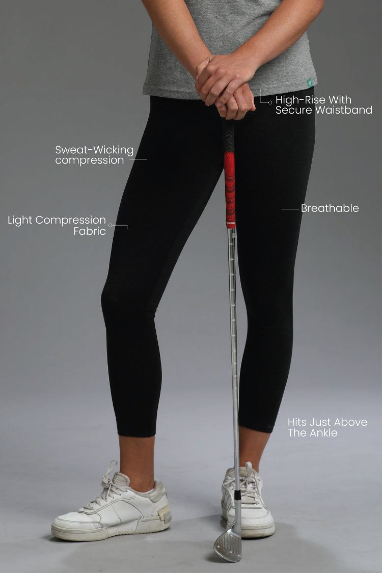 Person wearing black leggings with text highlighting features, holding a golf club on a gray background || Black Heather