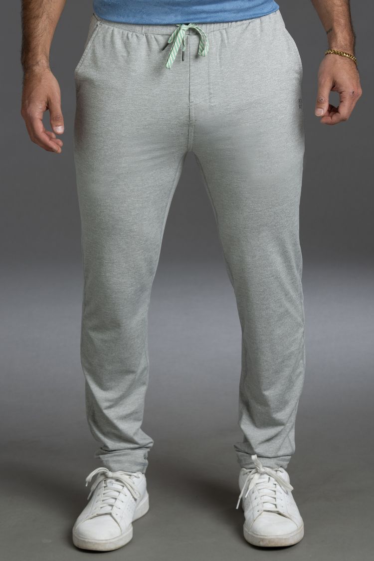 Person wearing gray sweatpants and white sneakers on a gray background