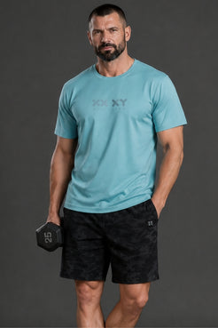 Man wearing a light blue t-shirt and black shorts holding a dumbbell against a gray background || Underseas