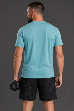 Man holding a dumbbell wearing a light blue t-shirt and black shorts on a gray background || Underseas