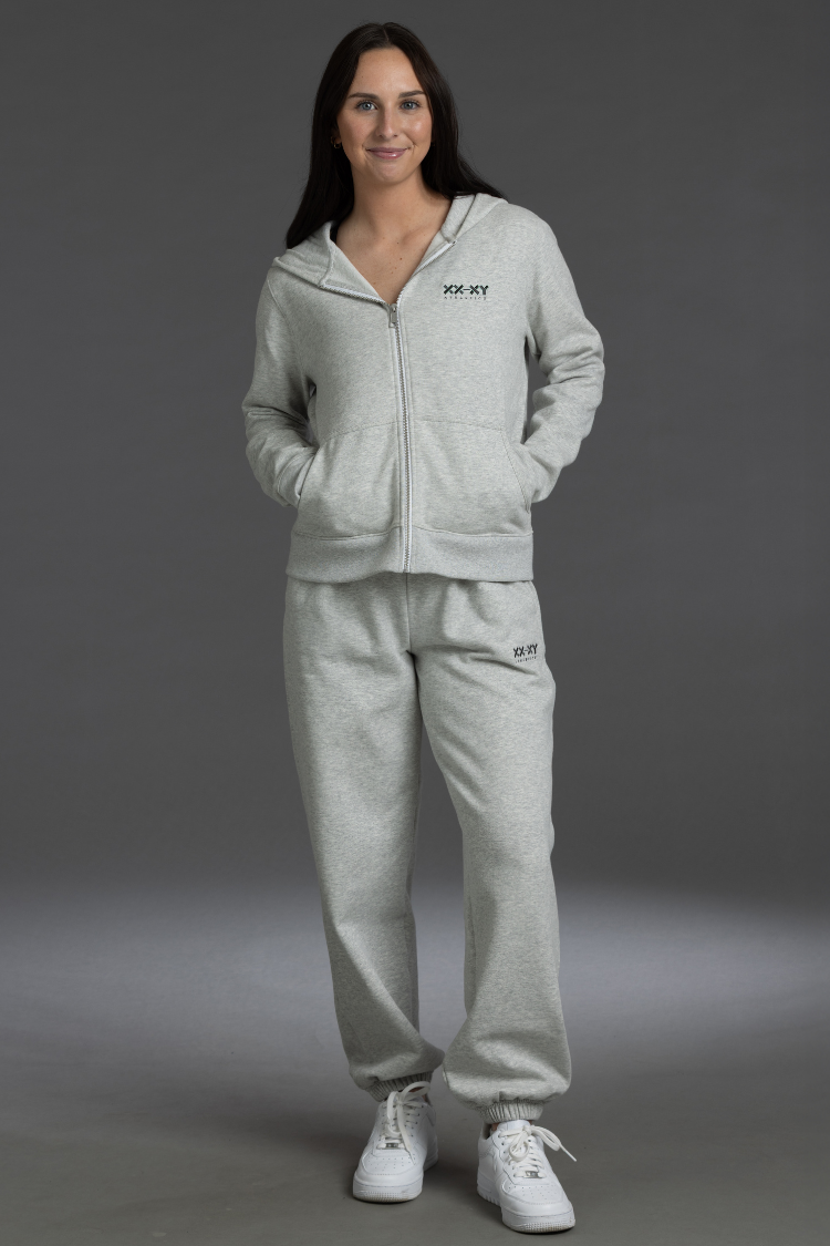 Woman wearing a gray tracksuit with a brand logo on a gray background || Light Heather Gray