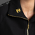 Black jacket with gold zipper and a yellow XXXY brooch || Gold