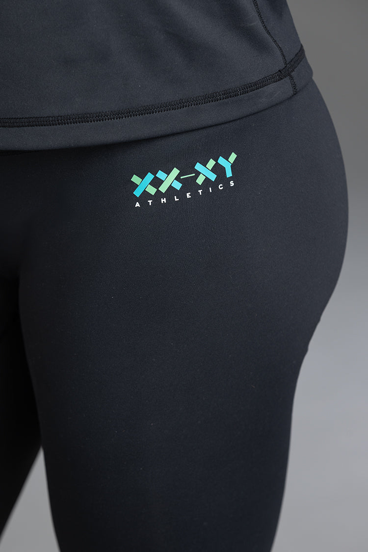 Black athletic leggings with a logo on the leg against a gray background