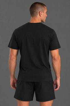 Male model showcasing the plain black back of an XX-XY Athletics crewneck T-shirt, paired with black athletic shorts against a gray studio background. || Black