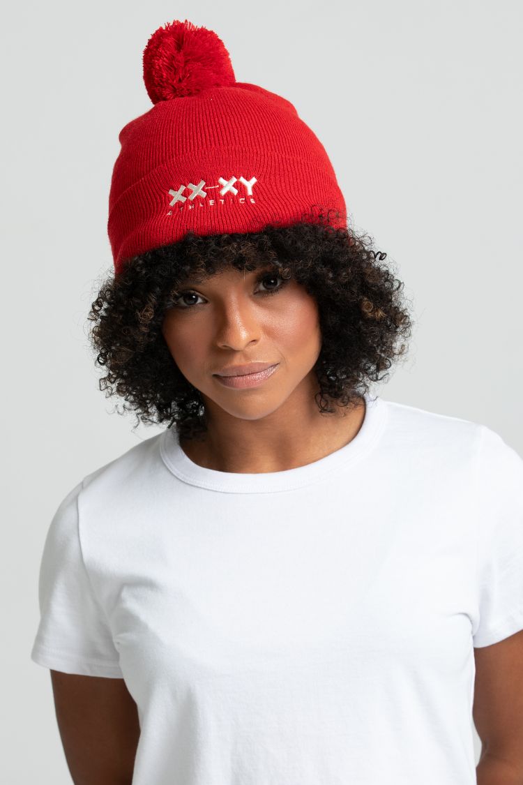 Person wearing a red beanie with a pom-pom on a plain background || red