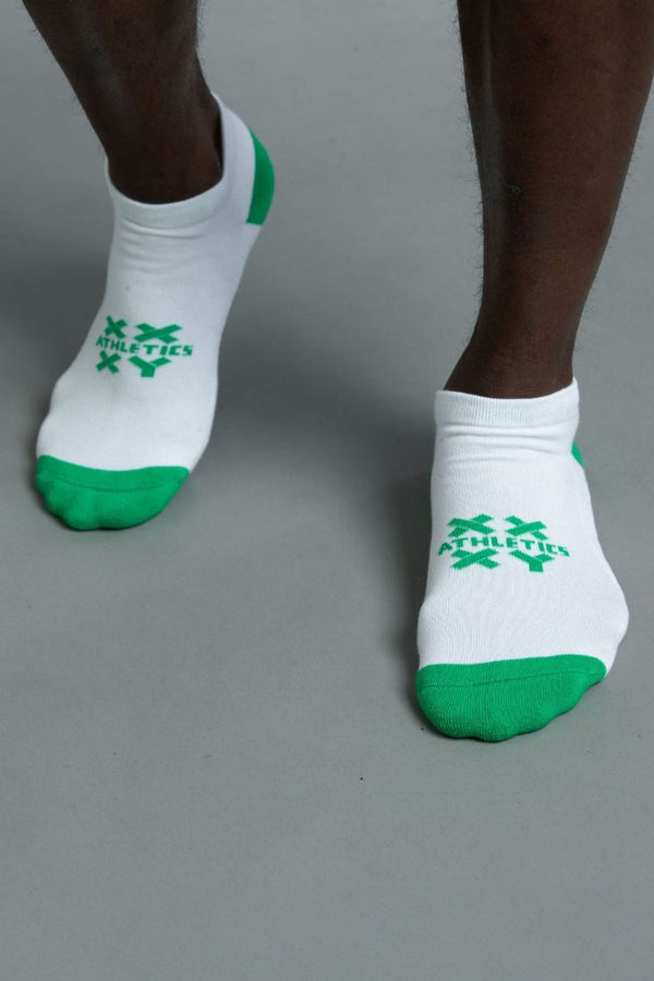 White socks with green accents worn by a person on a gray background || white