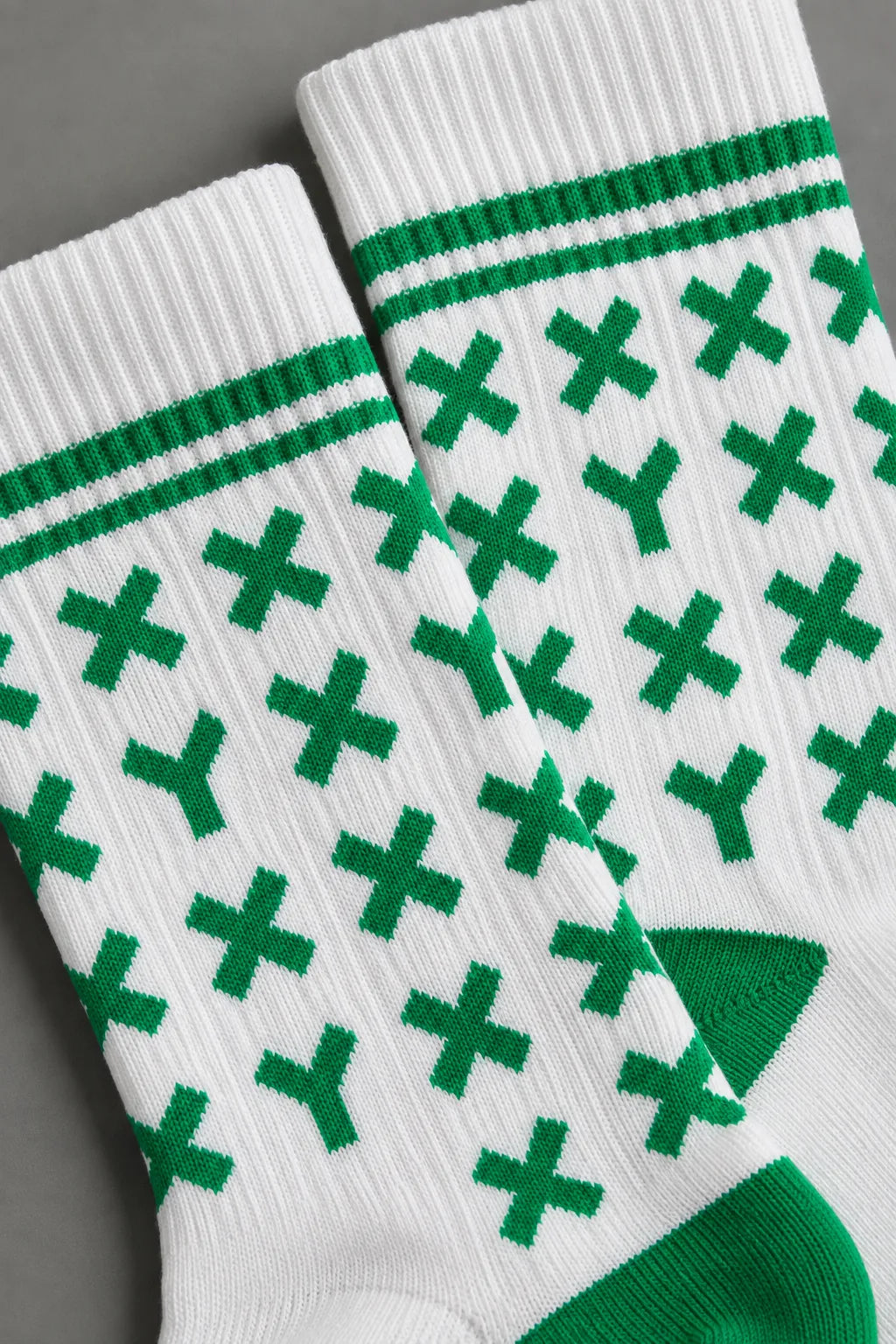 Zoomed in shot of white XX-XY Athletics crew socks with green X and Y's.