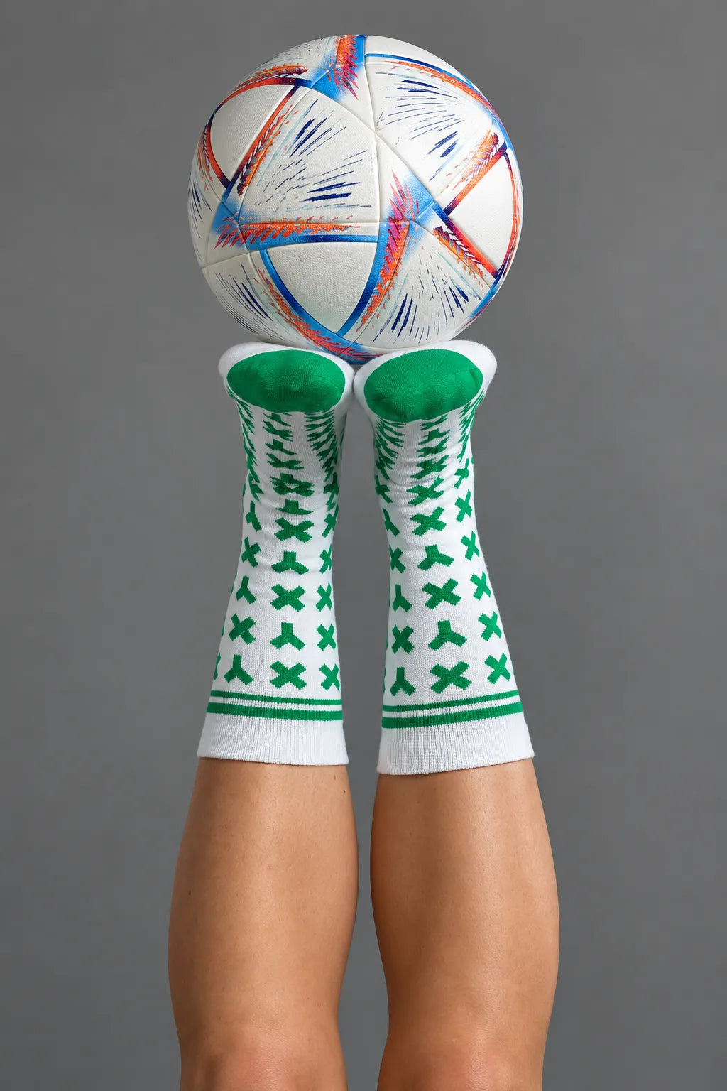 Person wearing green and white patterned socks with a soccer ball on a gray background