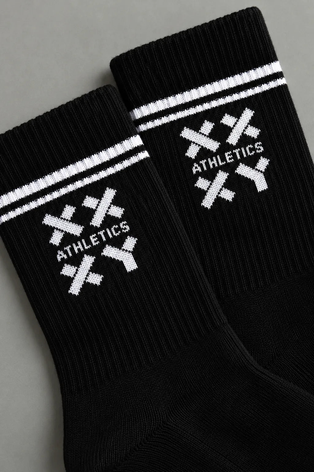 Close-up of black XX-XY Athletics crew socks featuring white stripes and a white knit logo.