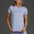 Woman wearing a Lavender t-shirt and shorts with a logo on a gray background || Lavender Gray