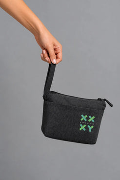 Hand holding black XX-XY Athletics wristlet pouch by the strap against a gray background || Black