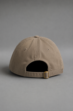 A structured baseball cap in a warm taupe-beige color, shown from the back to display the adjustable strap and gold-tone metal buckle, set against a solid gray studio background. || Mocha