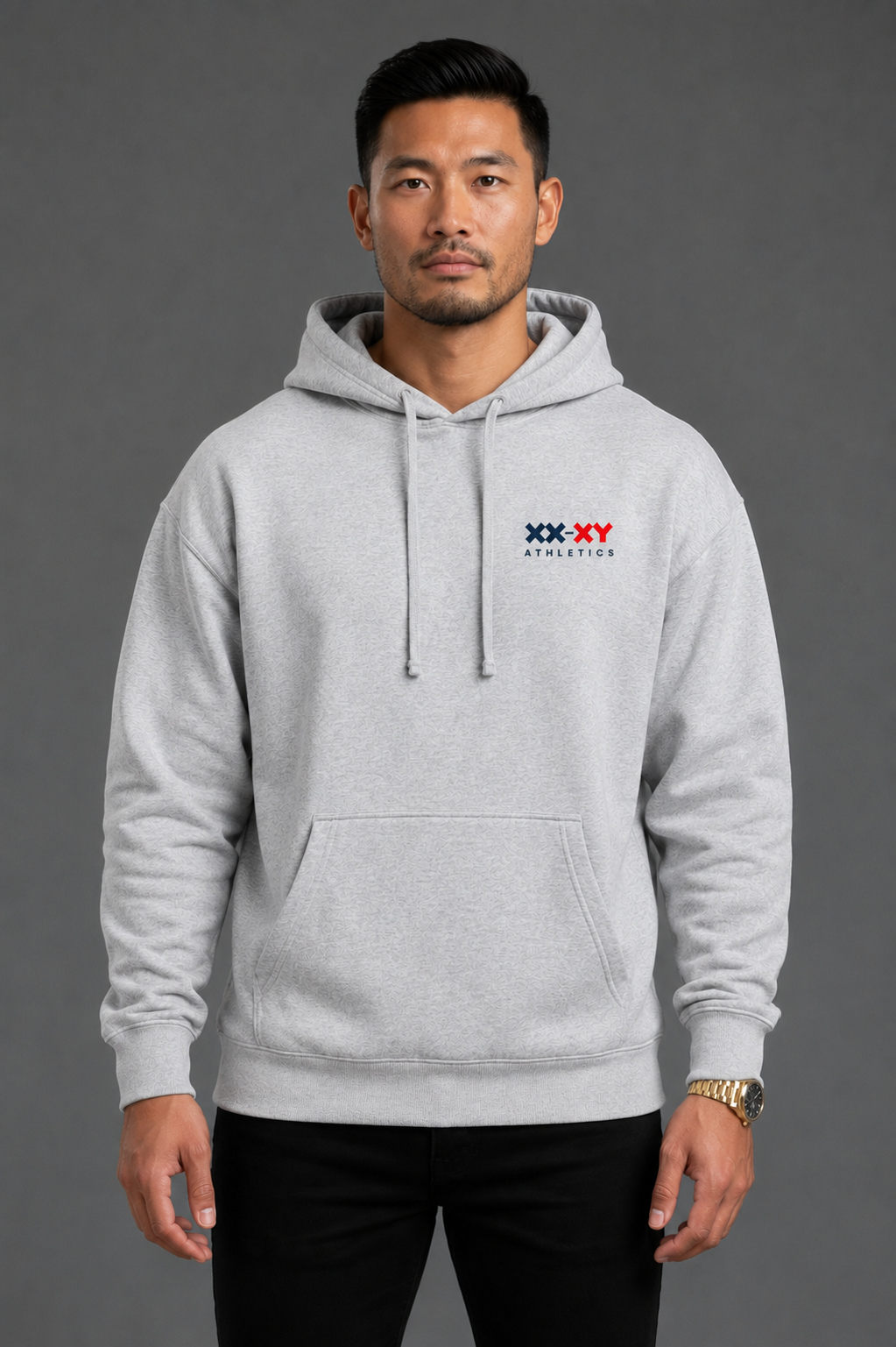 A man wearing a light gray heather pullover hoodie with a small red, white, and blue 'XX-XY AFFECTION' chest graphic, posed against a solid dark gray studio background.