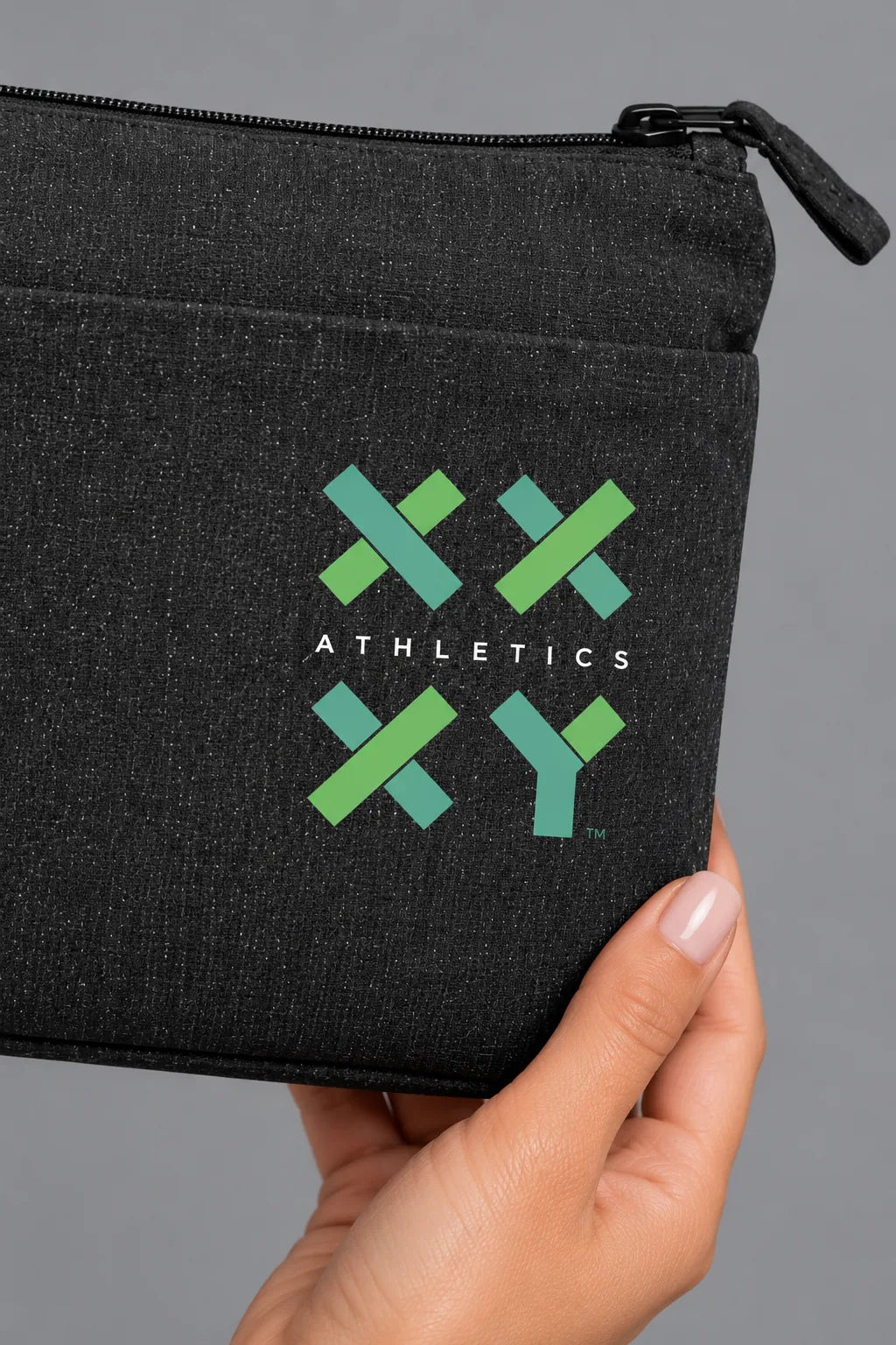 Close-up of green XX-XY Athletics logo printed on black recycled canvas wristlet pouch