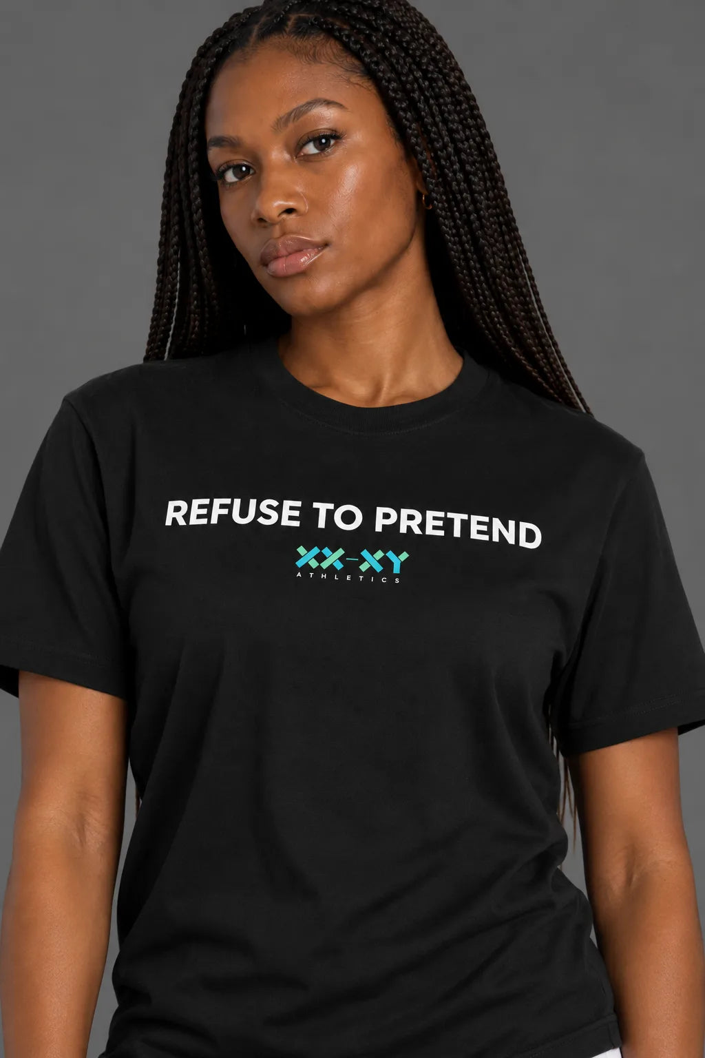 Close-up of female model wearing black Refuse to Pretend t-shirt featuring white lettering and turquoise XX-XY Athletics logo on chest. || Black