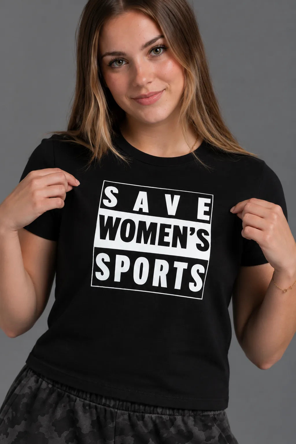 Close-up of a female model holding a black tee to highlight the white Save Women’s Sports graphic. || Black