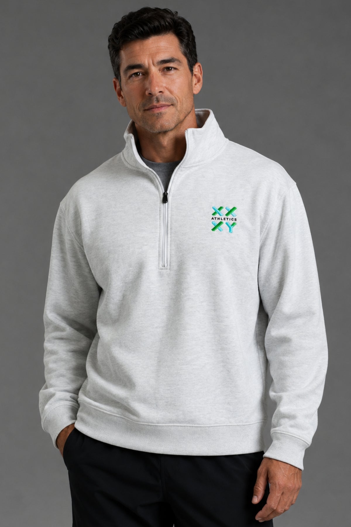 Male model wearing a light gray XX-XY Athletics quarter-zip fleece, shown in a close-up studio shot highlighting the embroidered chest logo. || Light Heather Gray