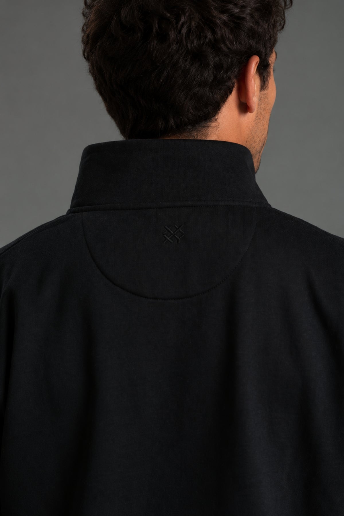 Person wearing a black jacket and shorts on a gray background