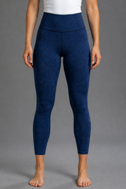 A model from the waist down wearing high-waisted, heathered navy blue leggings against a solid gray studio background. || Navy