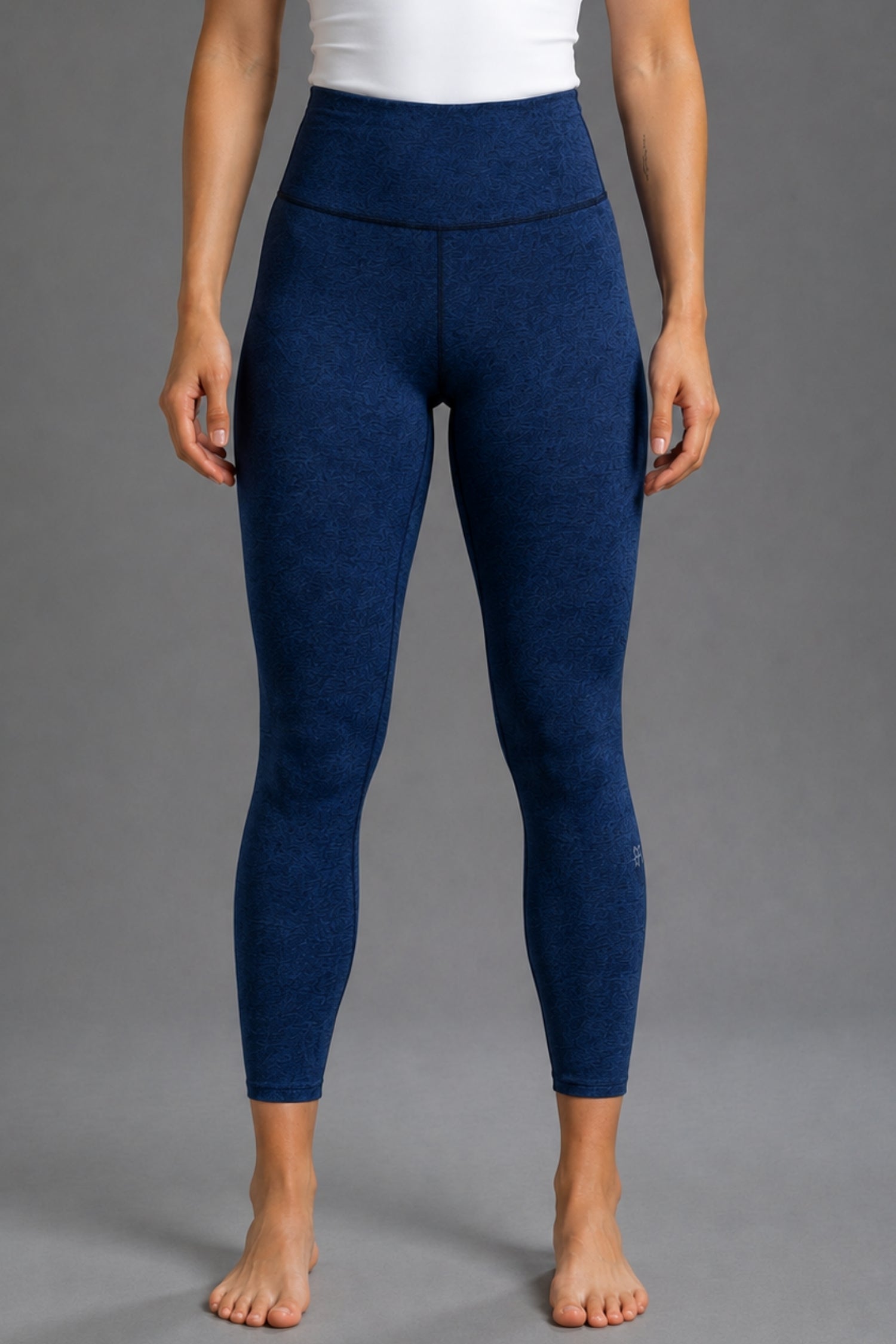 A model from the waist down wearing high-waisted, heathered navy blue leggings against a solid gray studio background. || Navy
