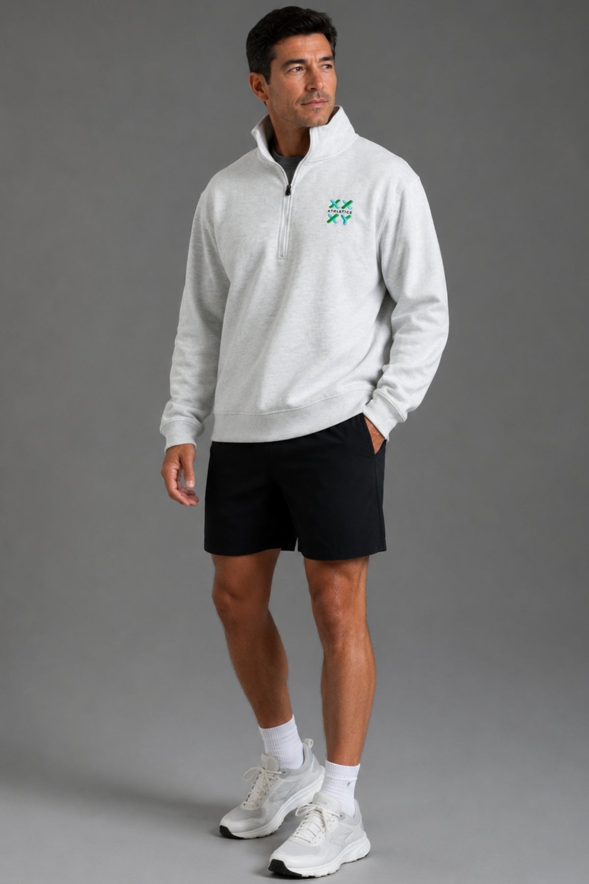 Male model wearing a light gray XX-XY Athletics quarter-zip fleece, shown in a far away studio shot.