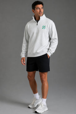 Male model wearing a light gray XX-XY Athletics quarter-zip fleece, shown in a far away studio shot. || Light Heather Gray