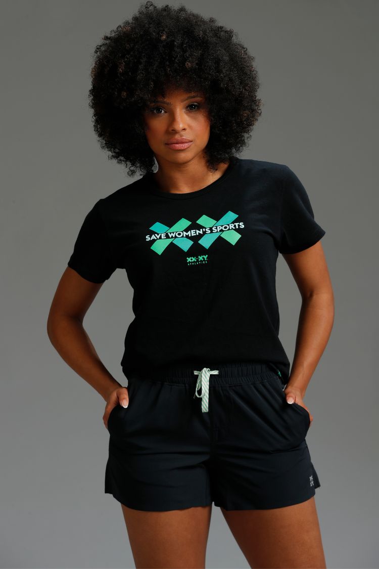 Person wearing a black t-shirt with green text and black shorts on a gray background || black