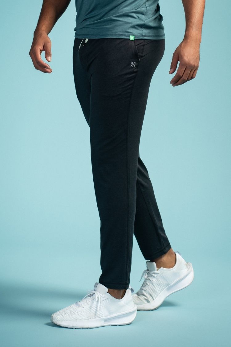 Person wearing black pants and white sneakers on a light blue background || black