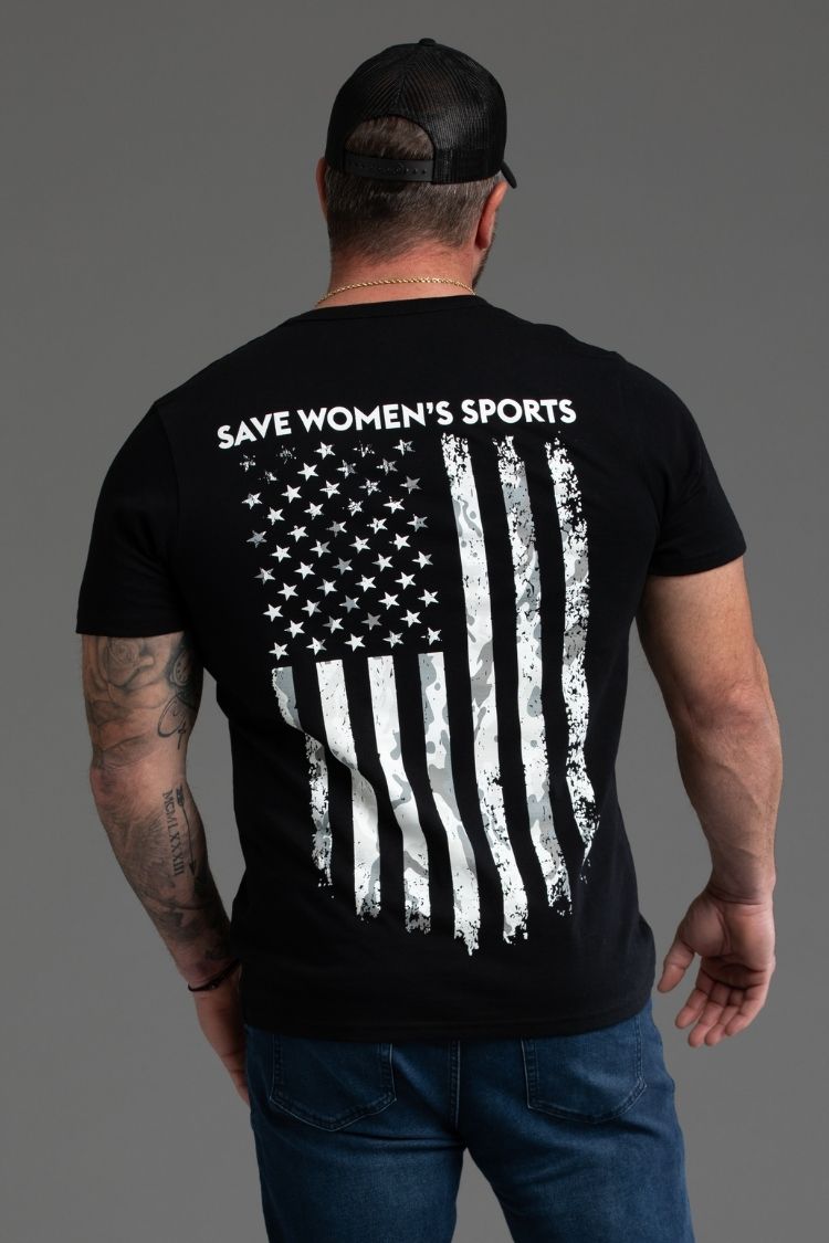 Man wearing a black t-shirt with an American flag and 'Save Women's Sports' text on the back, against a gray background. || black