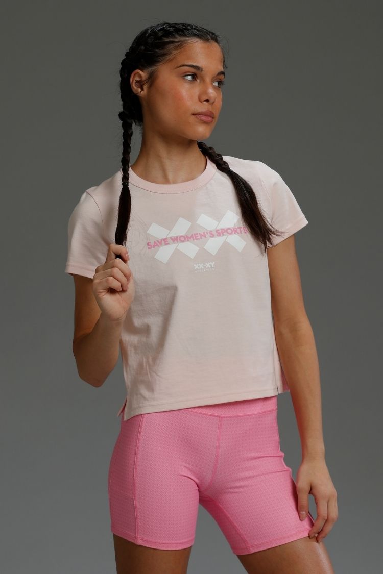 Woman wearing a light pink t-shirt with text and pink shorts on a gray background || Light Pink