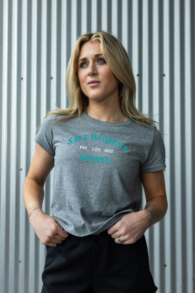Woman wearing a gray t-shirt with text against a corrugated metal background