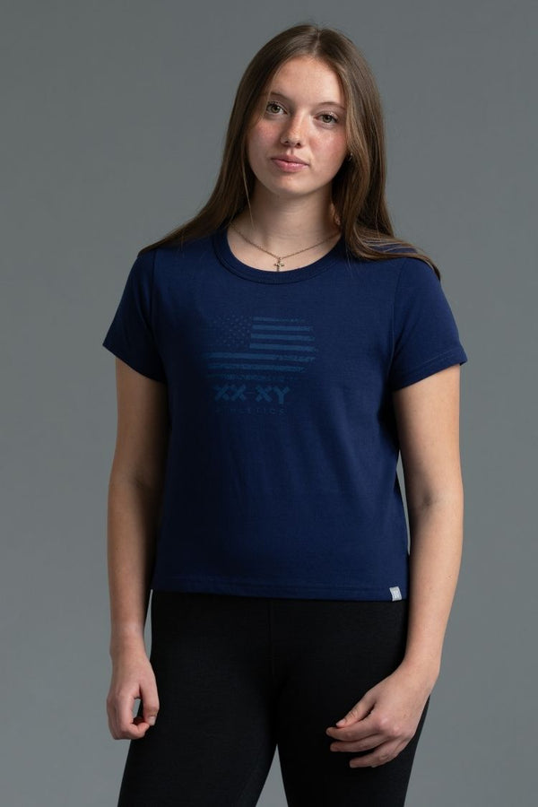 Person wearing a blue t-shirt with a logo on a gray background || Navy