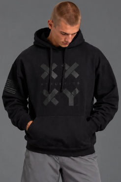 Male model looking down while wearing a black XX-XY Athletics hoodie with gray shorts. || Black