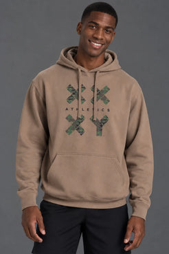 Male model smiling while wearing a mocha XX-XY Athletics camo graphic hoodie with black shorts. || Mocha