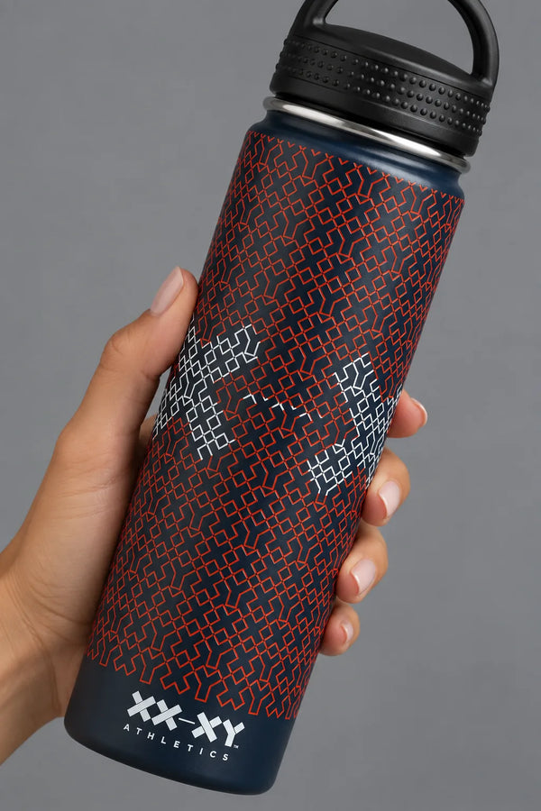 A 32 oz insulated stainless steel water bottle by XX-XY, featuring a dark navy blue body with a red geometric pattern and white geometric accents, topped with a black lid and carrying loop, set against a neutral gray background. || Navy Patriotic