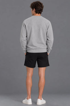 Male model showcasing the plain back of the XX-XY Athletics Crewneck Sweatshirt, paired with black shorts against a gray studio background || Heather Gray