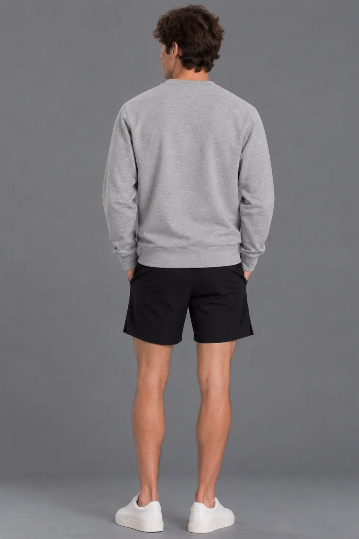 Male model showcasing the plain back of the XX-XY Athletics Crewneck Sweatshirt, paired with black shorts against a gray studio background || Heather Gray