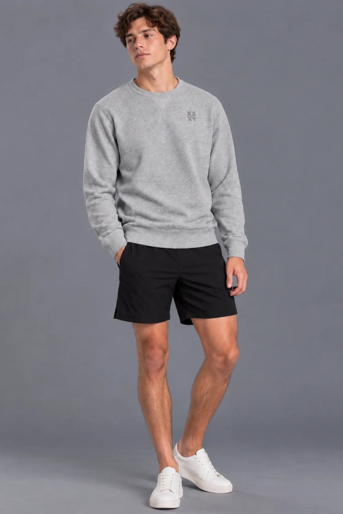 Male model smiling while wearing the XX-XY Athletics Crewneck Sweatshirt, black shorts and white sneakers