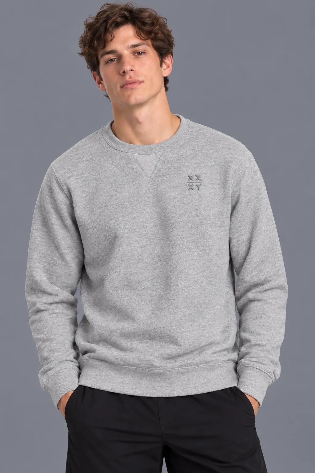 Male model wearing the XX-XY Athletics Crewneck Sweatshirt with tonal embroidered chest logo, paired with black shorts against a gray background