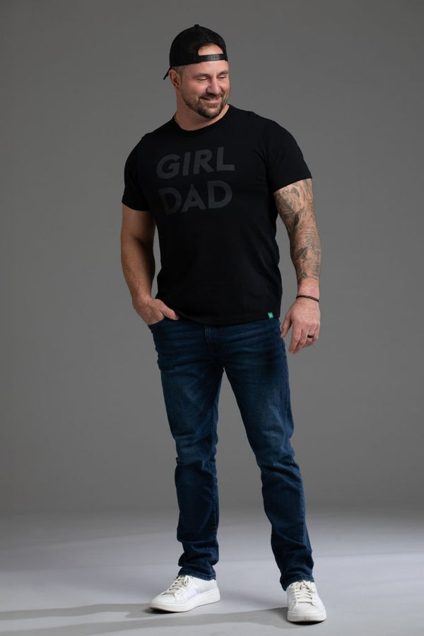 Man wearing a black t-shirt with 'GIRL DAD' text, blue jeans, and white sneakers on a gray background || black