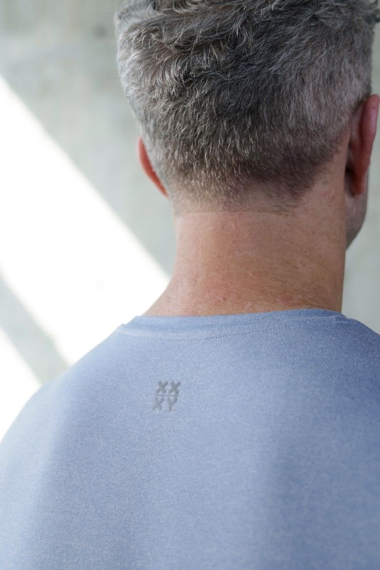 Back view of a person wearing a light blue shirt with logo || cerulean blue heather